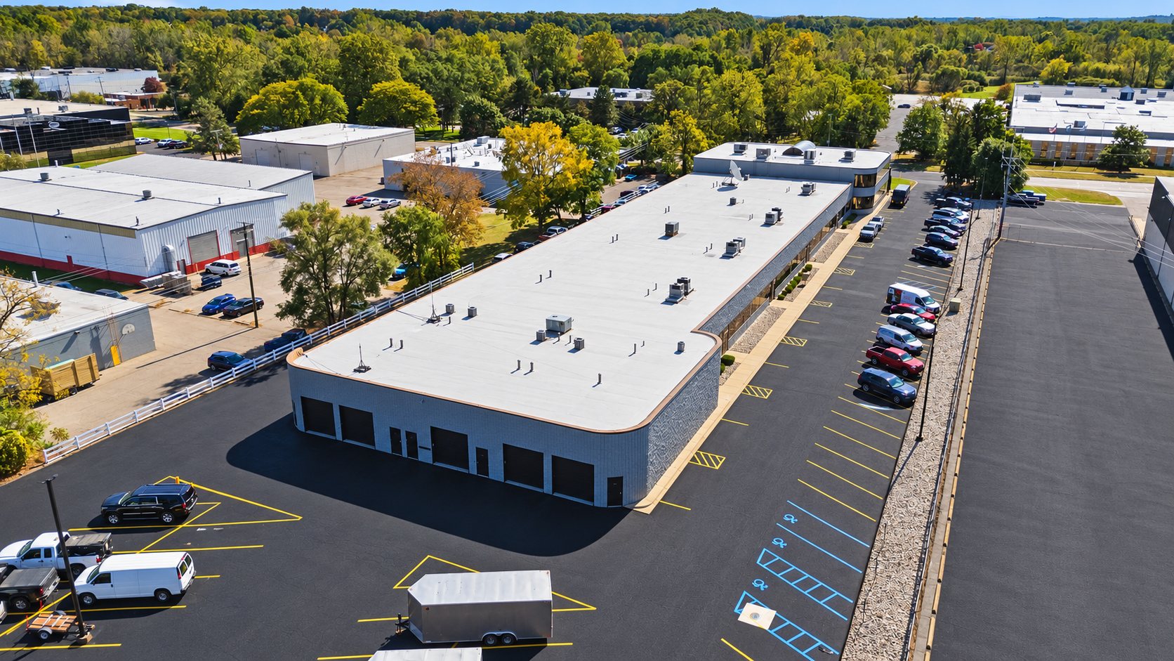 Aerial view of Z Novi Commons showing the white membrane roof with rooftop HVAC units and freshly sealed, striped parking lot