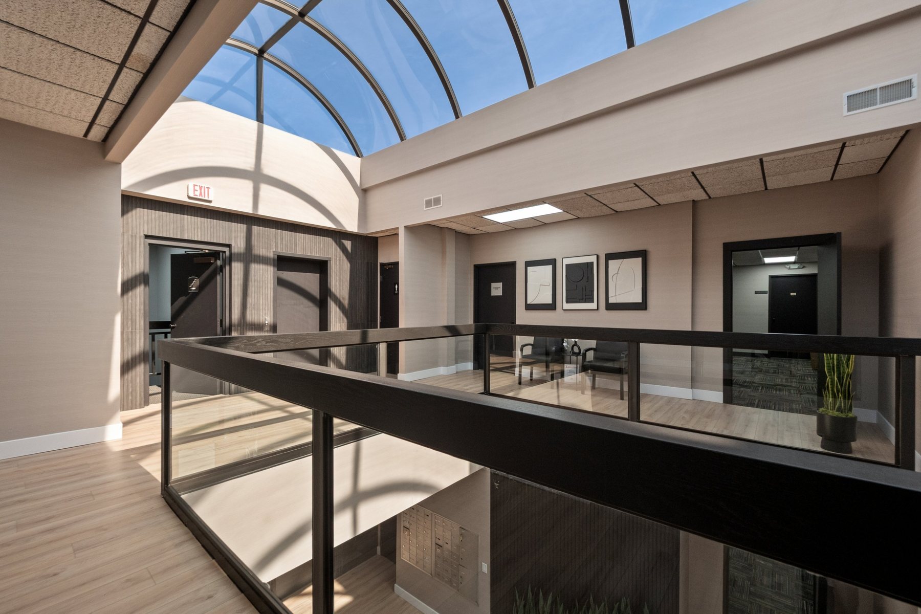 Clean second-floor lobby with framed art, waiting chairs and glass balcony under the skylight