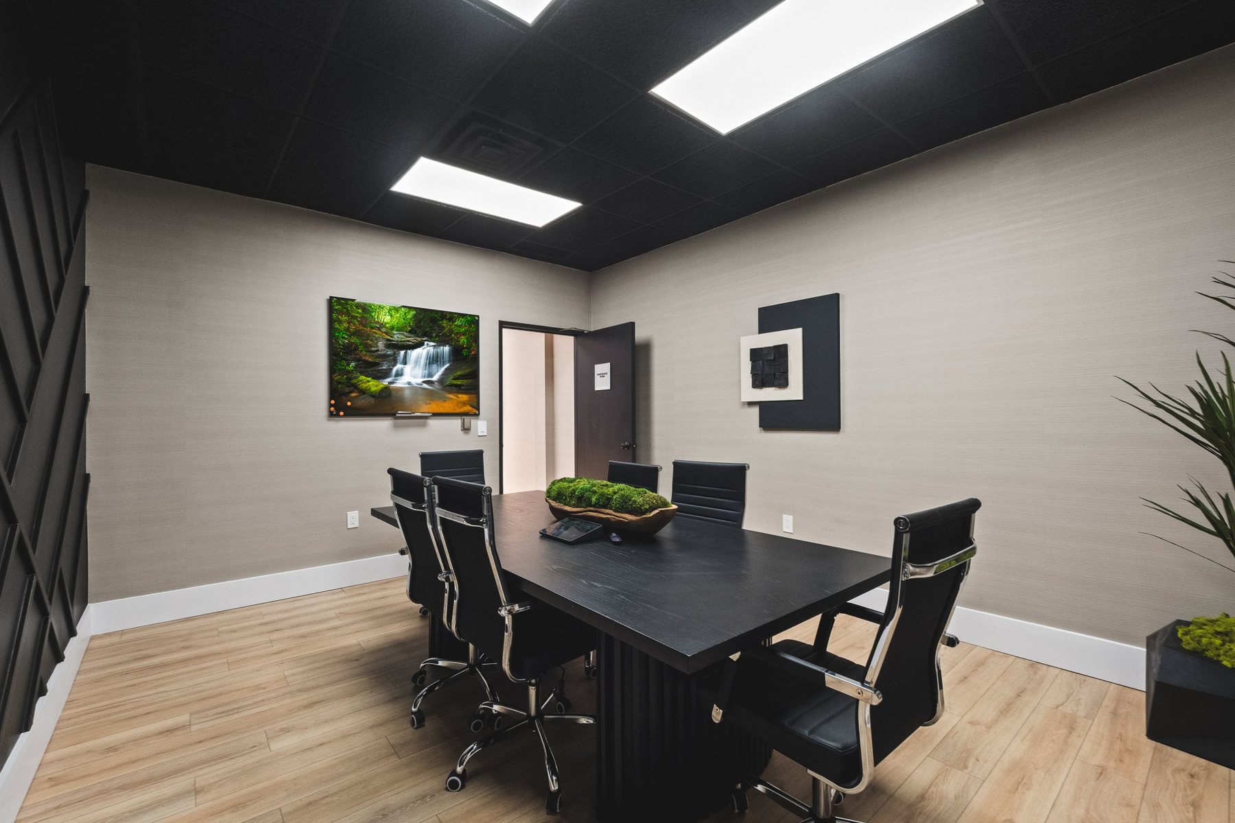 Modern conference room with black table, executive chairs and wall display
