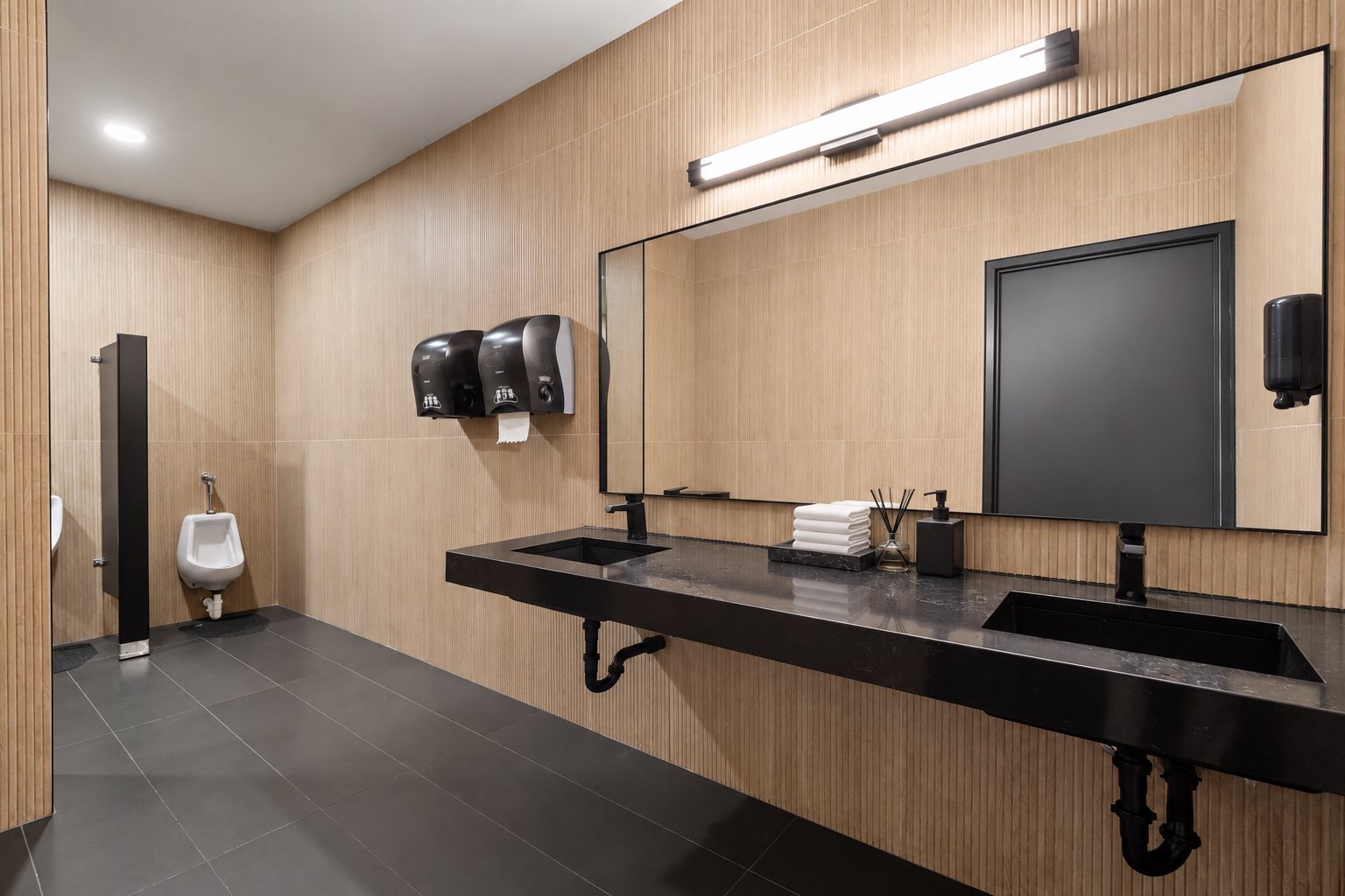 Renovated men's room in the private office area with wood-look tile, double vanity and black fixtures