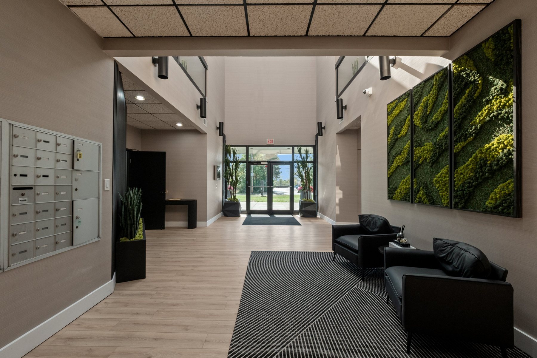Secure main entrance and lobby with tenant mailboxes, moss wall art and lounge chairs