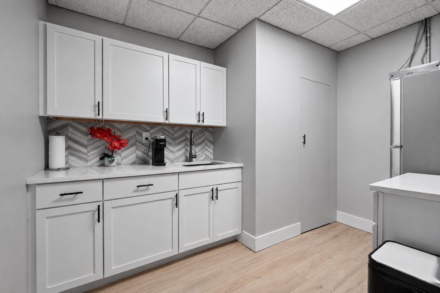 Shared kitchenette with white cabinets, quartz counter and coffee maker