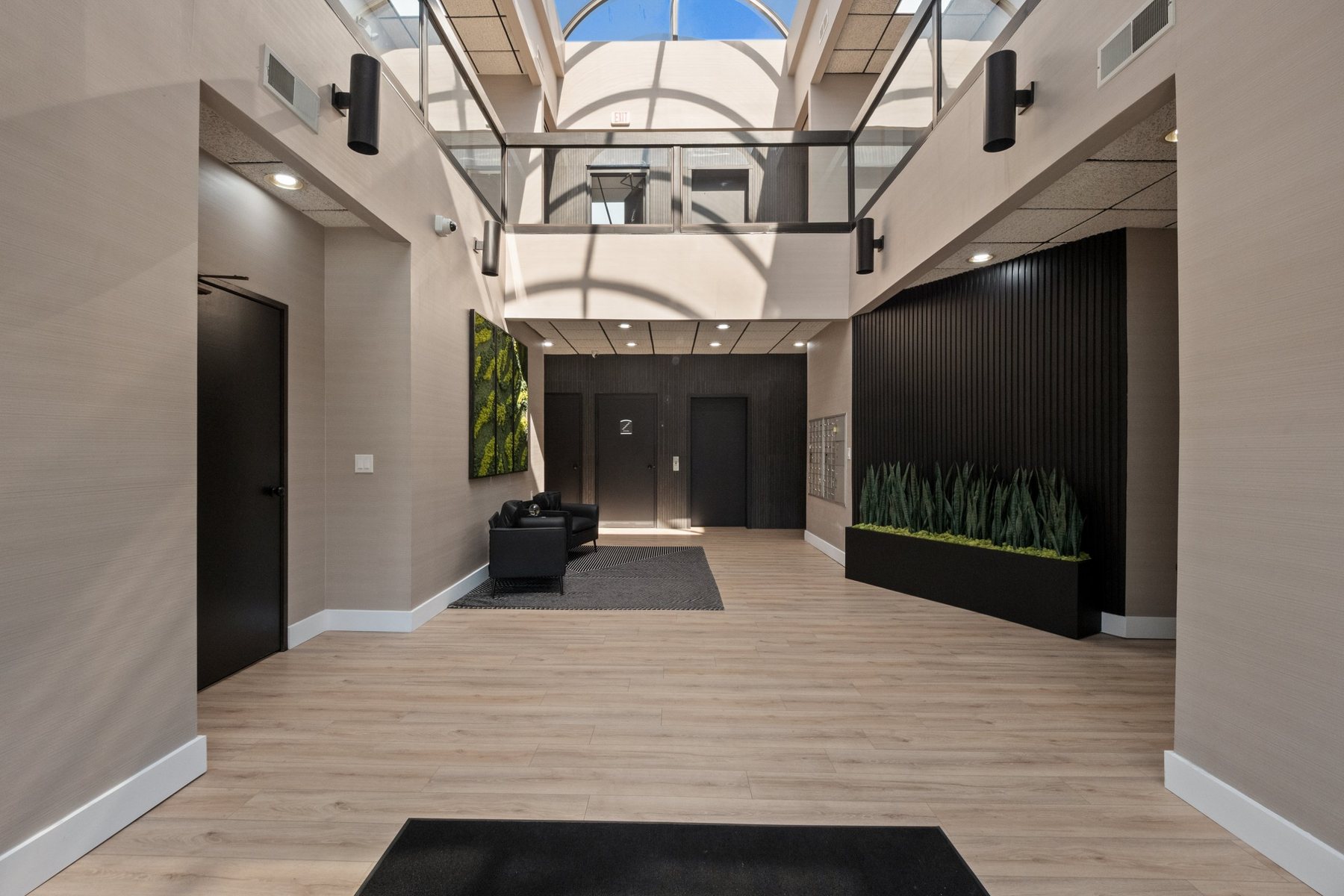 Two-story first-floor lobby at Z Novi Commons with arched skylight, glass balcony, lounge seating and mailboxes